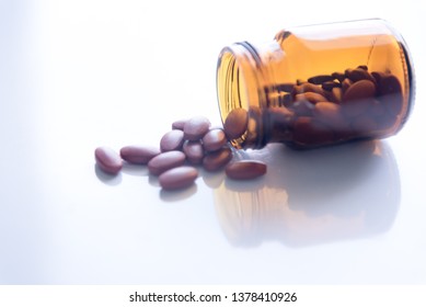 Tablets Pills Spilling Out Of Pill Bottel On White Background.