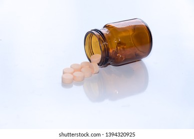 Tablets Pills Spilling Out Of Pill Bottel On White Background.