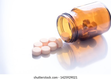 Tablets Pills Spilling Out Of Pill Bottel On White Background.