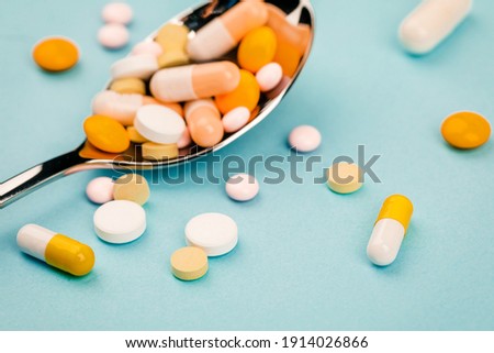 The tablets are randomly scattered around the spoon on a blue background.