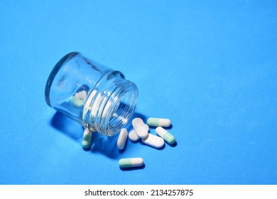 Tablets Scattered On Blue Background And In A Small Glass Container. 