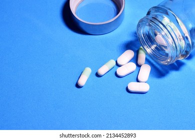 Tablets Scattered On Blue Background And In A Small Glass Container. 