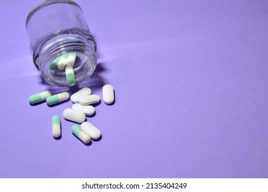 Tablets Scattered On Blue Background And In A Small Glass Container. 