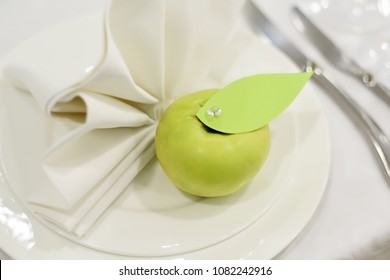 tableware and decorations for serving a festive table green apple on a white plate with a petal of cardboard 