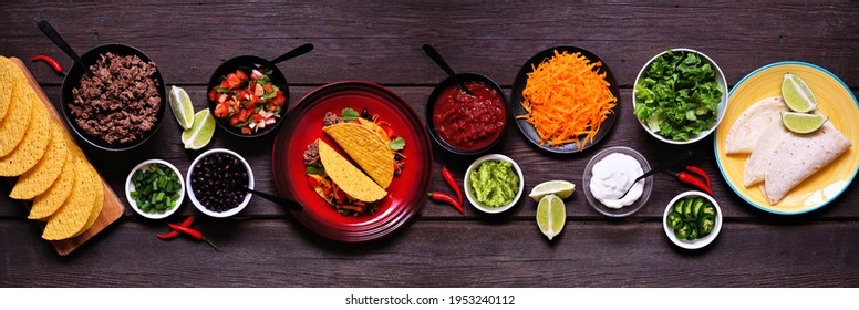 Taco Bar Table Scene With A Selection Of Ingredients. Overhead View On A Dark Wooden Banner Background. Mexican Food Buffet.