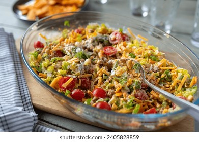 Taco salad with ground beef, cheddar cheese, tomatoes, romana salad and sour cream mixed up in bowl on a table - Powered by Shutterstock