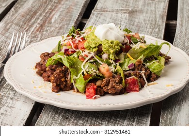 Taco salad on an antique platter on a weathered barn wood table