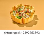 Taco salad in tortilla bowl with beef, cheese, corn and lettuce.