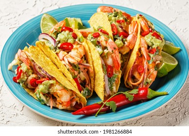 Taco Shells With Grilled Shrimps, Cabbage Salad, Lime And Guacamole On A Blue Plate On A White Table, Close-up