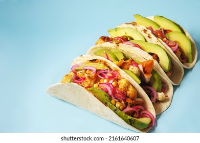 Tacos with avocado, cauliflower, corn on a blue background