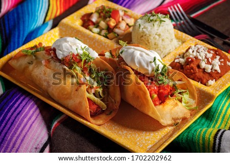 Tacos platter with rice, vegetables and sauce served on a yellow plate