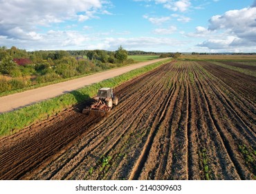Tactor with disk harrow on plowing field. Cultivated land and soil tillage. Tractor with disc cultivator on land cultivating. Agricultural tractor on soil cultivation field. Plough plowed.