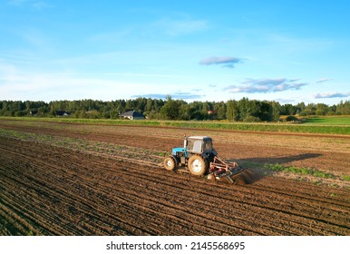 Tactor with disk harrow on plowing field. Cultivated land and soil tillage. Tractor with disc cultivator on land cultivating. Agricultural tractor on soil cultivation field. Plough plowed.
