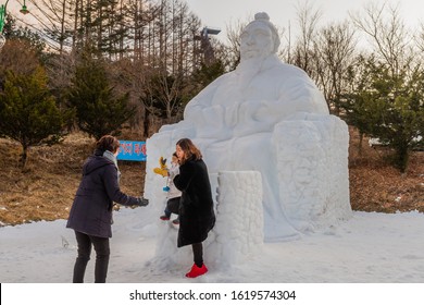 Taebaek, South Korea; January 12, 2020: Unidentified Mother Removing Child From Ice Sculpture Of King Sejeong While Another Woman Watches At Taebaek Snow Festival.