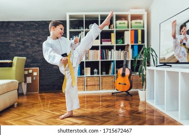Taekwondo boy exercising at home in living room.