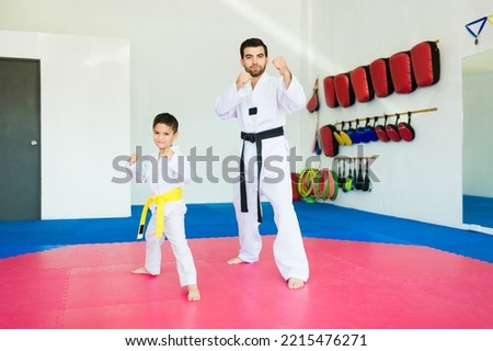 Taekwondo coach and toddler student doing a karate pose during a martial arts class