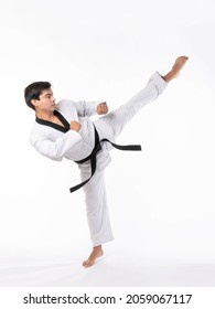 Golpe alto en Taekwondo - maestro de artes marciales en el cinturón negro taekwondo, hombre apuesto que muestra alta posición durante el entrenamiento de combate aislado en el fondo blanco 