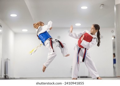 Taekwondo kids in doboks in action practicing combat in martial art school.