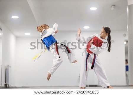 Taekwondo kids in doboks in action practicing combat in martial art school.