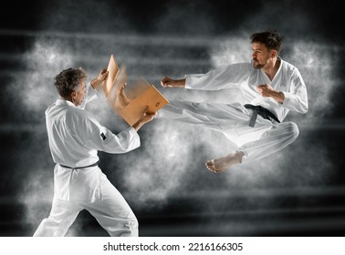 Taekwondo master breaks a wooden board with his foot. Smoke background - Powered by Shutterstock