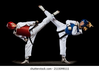 Taekwondo Practitioners, Two Young Women Wearing Doboks Training Together Isolated Over Dark Background. Concept Of Sport, Skills. Concept Of Sport, Education, Skills, Workout, Health