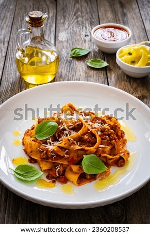 Tagliatelle con ragù alla bolognese - pasta with minced meat and tomato sauce on wooden table
