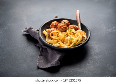 Tagliatelle avec boulettes de viande et sauce tomate sur fond noir. Concept culinaire italien. 