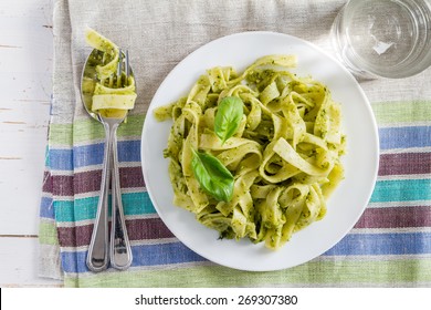 Tagliatelle Pasta With Pesto Sauce And Basil Leafs On White Plate, White Wood Background, Top View