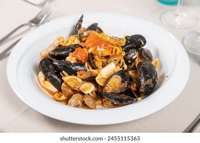 Tagliolini allo scoglio, homemade Italian pasta with mussels, clams, calamari, scampi, prawns and tomato. Seafood tagliolini - Powered by Shutterstock