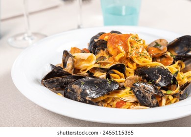 Tagliolini allo scoglio, homemade Italian pasta with mussels, clams, calamari, scampi, prawns and tomato. Seafood tagliolini