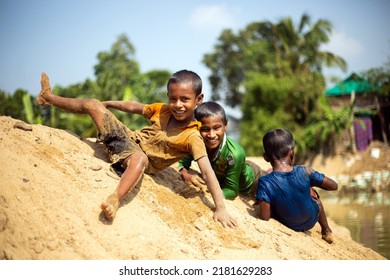 Taherpur, Bangladesh – November 05, 2019: Children Tumbling Down From The Sand Hill To The River Water. Children Enjoying School Vacation During The Flood. Kids Playing And Toppling On The Riverbank