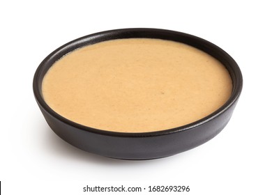 Tahini In A Black Ceramic Bowl Isolated On White.