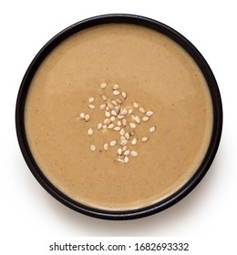 Tahini In A Black Ceramic Bowl Sprinkled With Sesame Seeds Isolated On White. Top View.