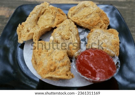 Tahu Walik, Inside Out Crispy Tofu Stuffed is a processed tofu snack fried in starch and other ingredients with Meatball Tahu Walik also known as Tahu Bakso in the black plate serve with spicy chilli