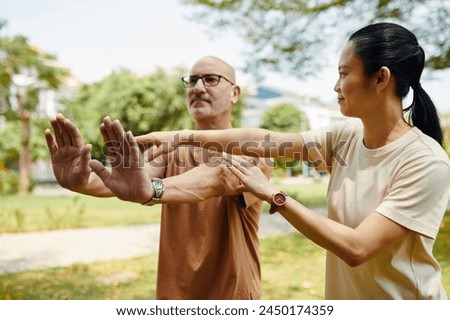 Tai chi instructor explaining g client how to keep arms straight when doing exercise