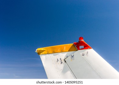 Tail Fin, Rudder And Beacon Lights, Small Single Engine Airplane With Old Paint And Bright Blue Sky.