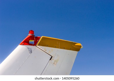 Tail Fin, Rudder And Beacon Lights, Small Single Engine Airplane With Old Paint And Bright Blue Sky.