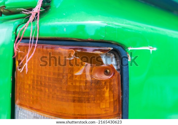 tail light\
green car. broken rear brake light. blue passenger car. dent and\
scratch on the rear fender. road\
accident