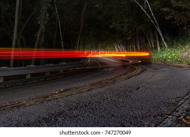 Tail Lights From Car At Night On Windy Forest Road. 