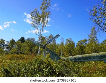 The tail section of a crashed helicopter with blades in the middle of the forest.                     