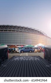 Tailgating background, looking out from the bed of a pickup truck, parking lot with cars and tents in background