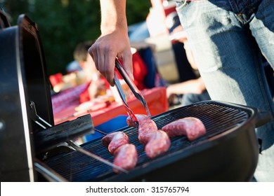 Tailgating: Man Grilling Sausages On Charcoal Grill For Party