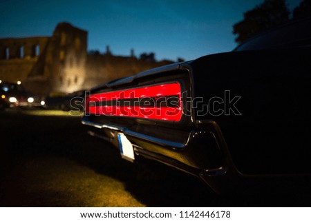Taillight of old classic muscle car is switched on at the night