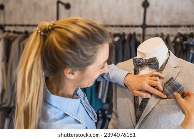 tailor adjusts a pocket square on a mannequin dressed in a suit and bow tie at a wedding store - Powered by Shutterstock