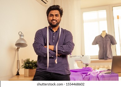 Tailor Asian Man Designer Sewing Clothes On Sewing Machine Next To Laptop Studio Workplace.