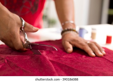 Tailor designer working of cutting piece of cloth with scissors
