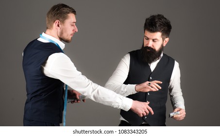 Tailor, Greedy Designer Wants More Money For Expensive Clothes. Overpayment Concept. Customer, Client Paying, Counting Money, Grey Background. Man With Beard Pay To Macho With Measuring Tape.