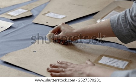 Tailor hands passing around pattern by soap on piece of cloth. Media. Details of clothing atelier.
