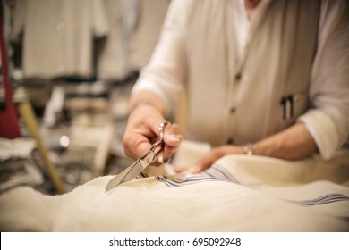 Tailor in his boutique cutting a piece of fabric