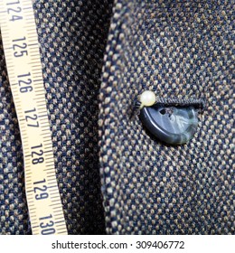 tailor measure tape and half buttoned button on green jacket close up